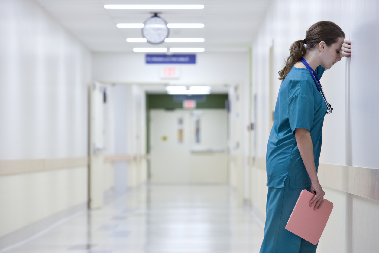nurse leaning against wall in corridor